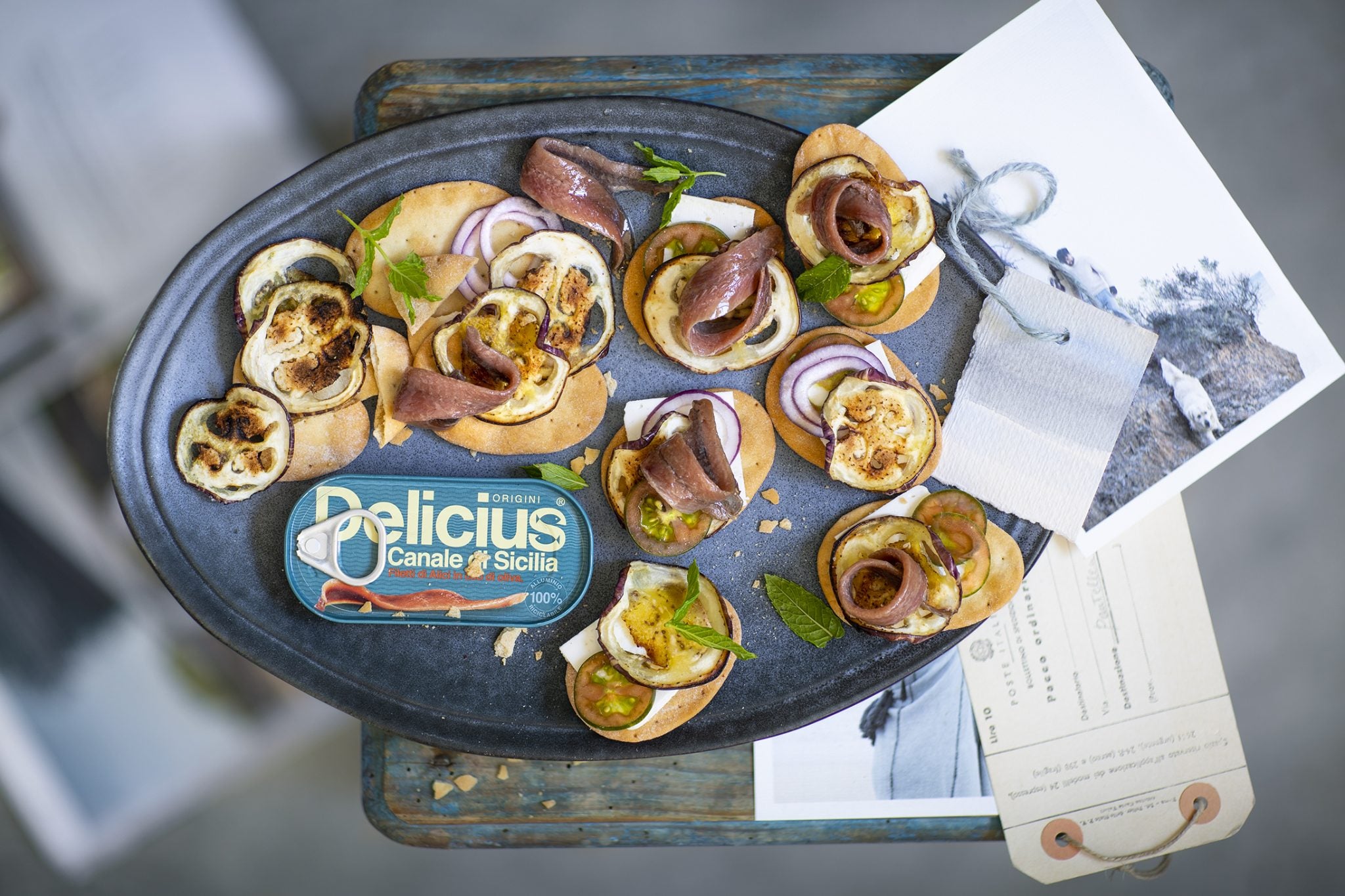 Tray of canapes with 'Delicius' branding on a rustic surface.
